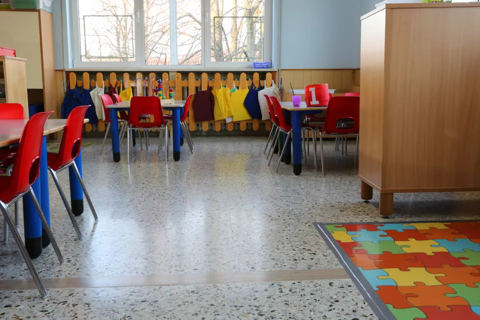 Empty kindergarten classroom with colorful chairs and floor mats.